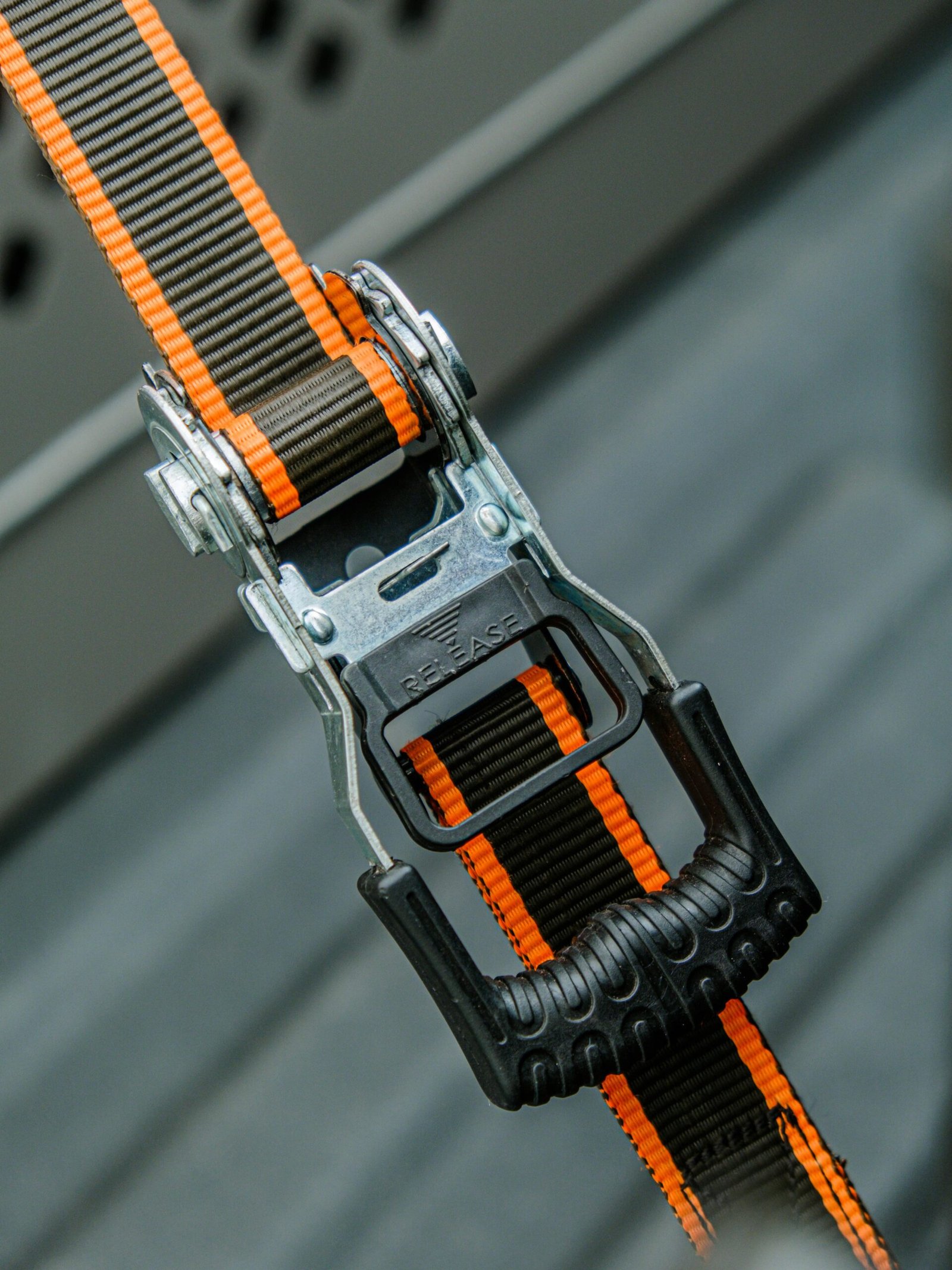 Durable ratchet strap with orange accents, ideal for secure cargo fastening.